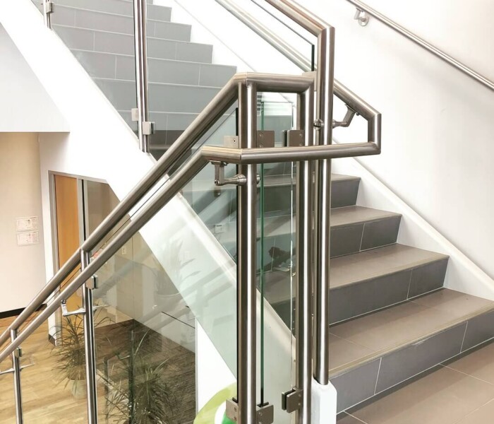 A view of Custom Glass railing in a close up shot going up stairs in a commercial building.