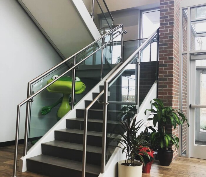 Interior Glass Railing Infill Panels going down black stairs on the inside of a commercial building.
