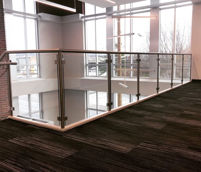 Stainless Steel Custom Glass Railing on the inside of a commercial building near windows.