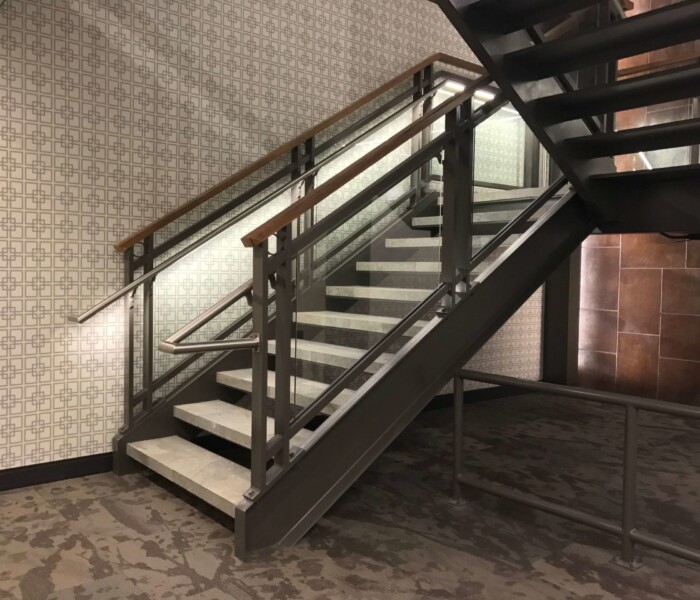 Architectural Custom Glass Railing with a black frame and stainless steel handrail with a wooden cap.