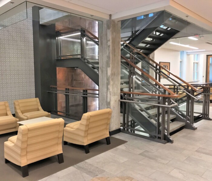 A view of stairs with interior glass railing with wood cap.