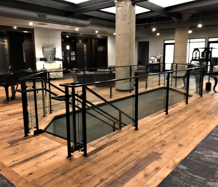 A side view of commercial architectural custom glass railings with assist rail.