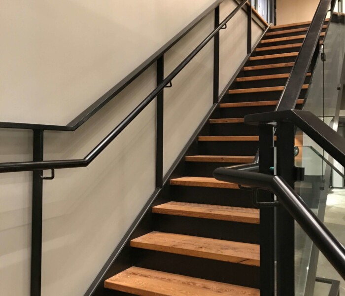 Commercial building with black custom glass railings with assist rail.